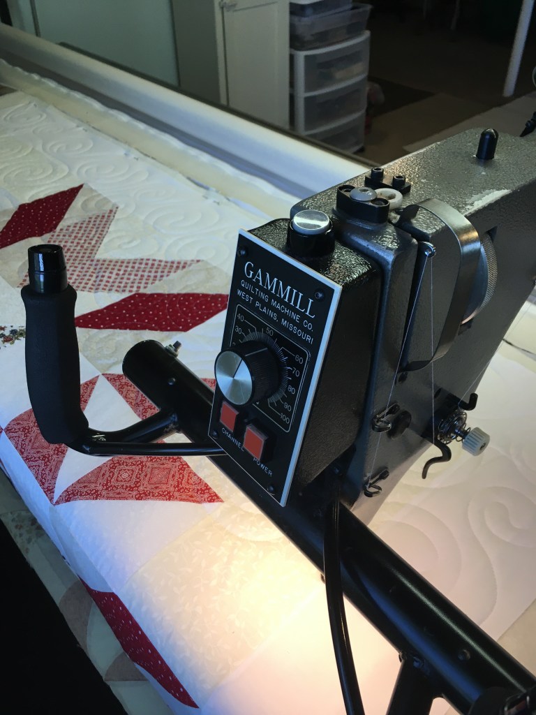 Gamil long-arm quilting machine with red and white quilt.