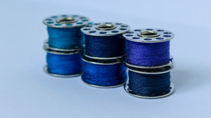 Six sewing bobbins filled with blue and purple thread