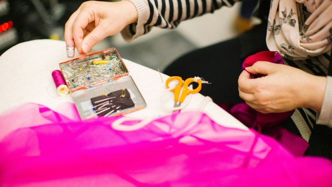 Photo on woman hand sewing on pink fabric