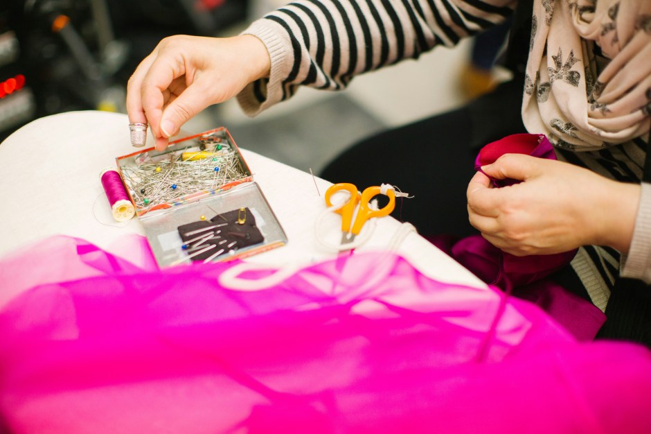 Photo on woman hand sewing on pink fabric